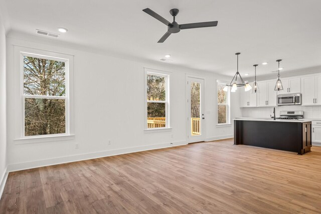 kitchen featuring appliances with stainless steel finishes, light hardwood / wood-style floors, white cabinetry, ceiling fan, and pendant lighting