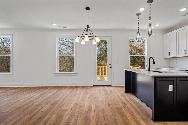 kitchen featuring a wealth of natural light, white cabinets, and light hardwood / wood-style floors