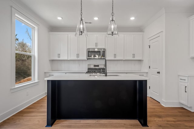 kitchen featuring a kitchen island with sink, light wood-style flooring, visible vents, and stainless steel appliances