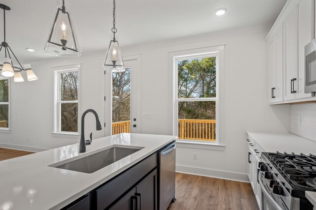 kitchen featuring hanging light fixtures, sink, appliances with stainless steel finishes, and light wood-type flooring