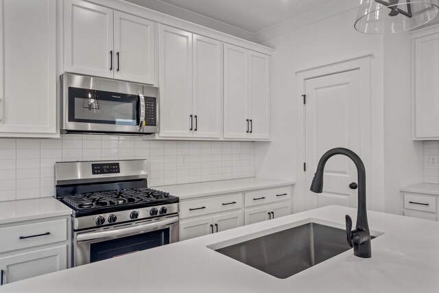 kitchen featuring backsplash, crown molding, stainless steel appliances, sink, and white cabinets