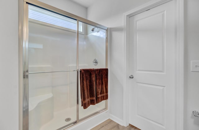 full bathroom featuring a stall shower, baseboards, and wood finished floors