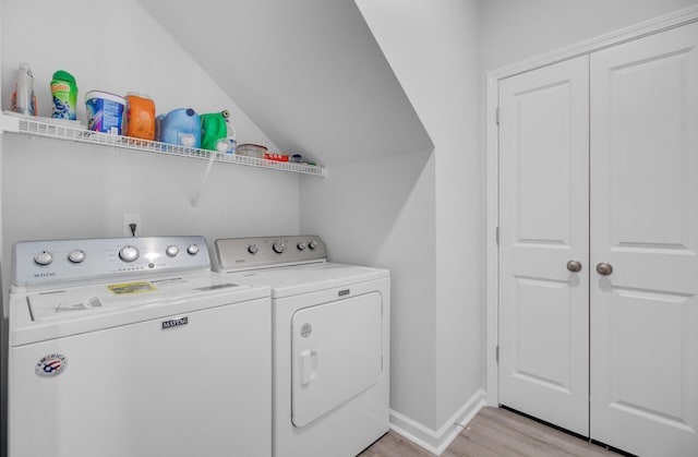 clothes washing area featuring washer and clothes dryer, light wood finished floors, and baseboards