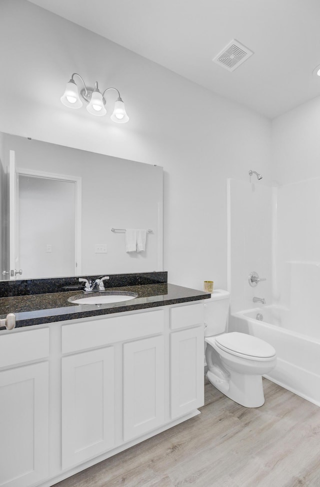 bathroom with toilet, bathtub / shower combination, wood finished floors, and vanity