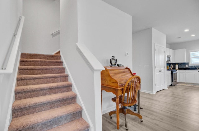 stairs featuring wood finished floors, baseboards, and recessed lighting