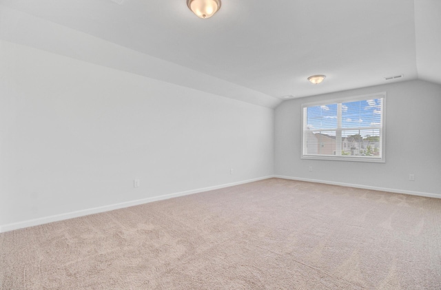 carpeted empty room with vaulted ceiling and baseboards