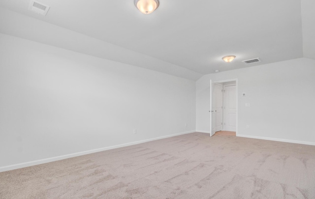 carpeted spare room featuring baseboards and lofted ceiling
