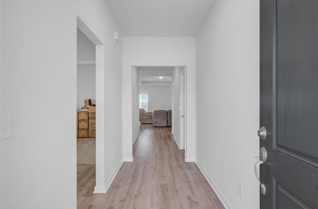 hall featuring light wood-style flooring and baseboards