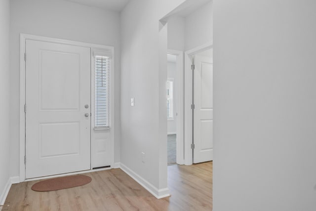 foyer with light wood-type flooring, baseboards, and healthy amount of natural light