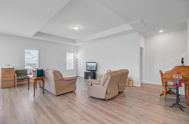 living room featuring a tray ceiling, light wood finished floors, baseboards, and recessed lighting