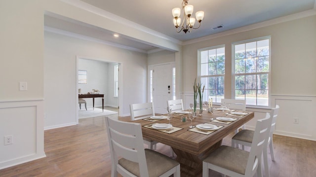 dining space featuring light hardwood / wood-style flooring, an inviting chandelier, and ornamental molding