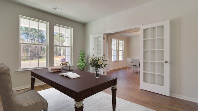 office with hardwood / wood-style floors, french doors, and a healthy amount of sunlight