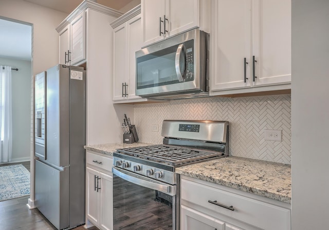 kitchen featuring stainless steel appliances, white cabinets, decorative backsplash, and light stone counters