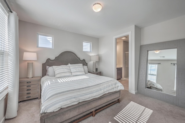 bedroom featuring ensuite bathroom and light colored carpet