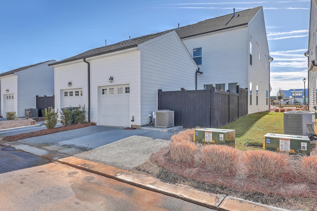 view of home's exterior with a garage, cooling unit, driveway, and fence