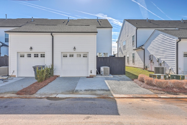 view of side of property featuring a garage, cooling unit, fence, and a shingled roof