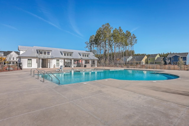 community pool with a residential view, fence, and a patio