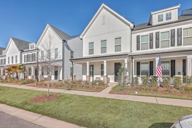 view of front facade featuring board and batten siding, a front yard, and a shingled roof