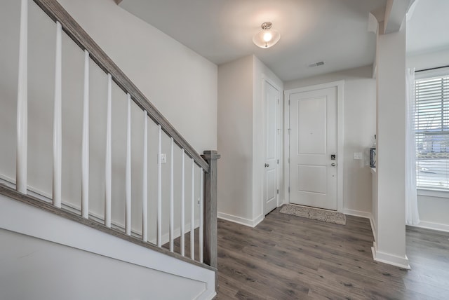 foyer with stairway, baseboards, visible vents, and dark wood-style flooring