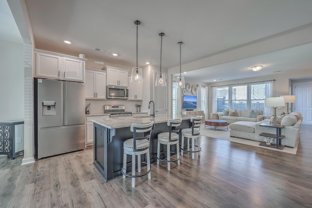 kitchen featuring hanging light fixtures, appliances with stainless steel finishes, a kitchen bar, and white cabinets