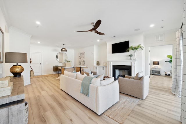 living room with light wood-type flooring, ceiling fan, and ornamental molding