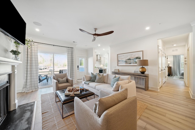 living room with ceiling fan, a premium fireplace, and light wood-type flooring