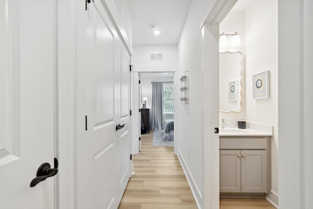 hallway with light hardwood / wood-style flooring and sink