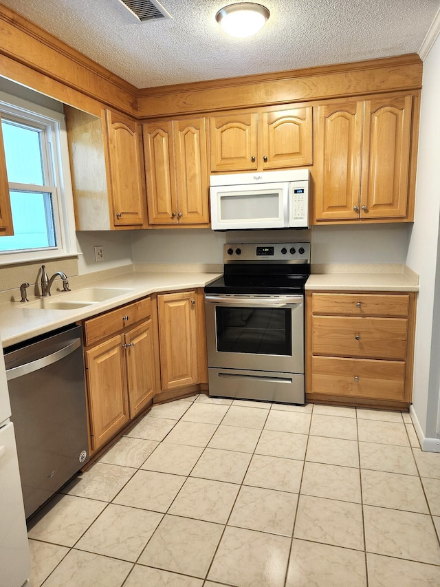 4029 Karen Dr, North Charleston, SC 29405 - kitchen featuring stainless steel appliances, a sink, a textured ceiling, light countertops, and light tile patterned floors