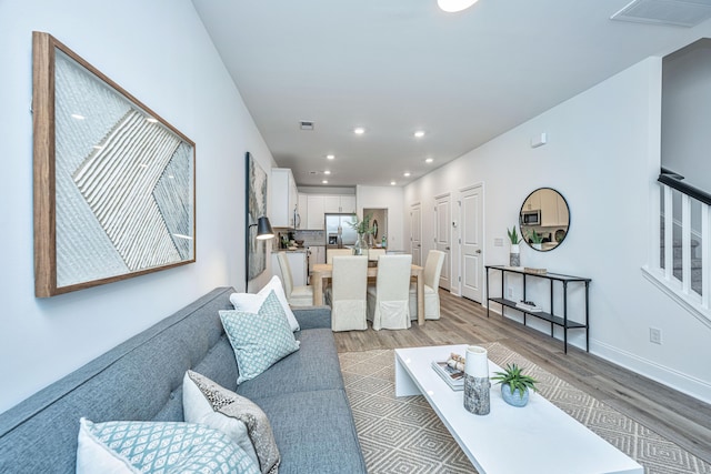 living room with light wood finished floors, baseboards, visible vents, and recessed lighting