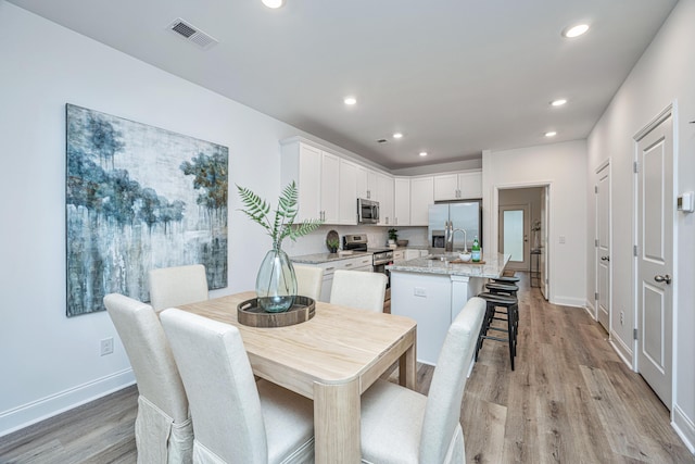 dining space with baseboards, light wood-style flooring, visible vents, and recessed lighting