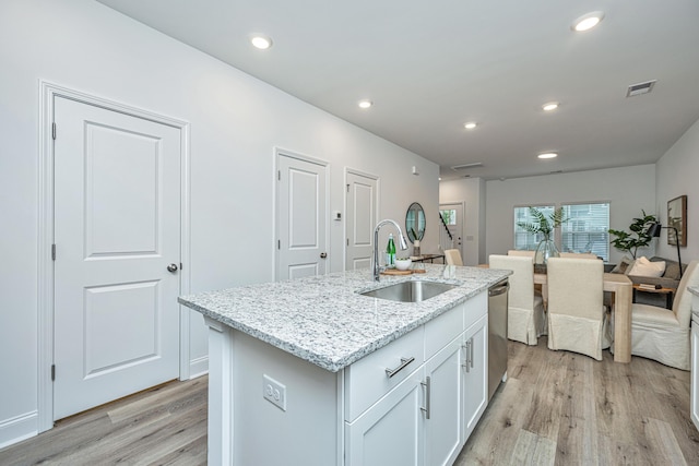 kitchen with a sink, visible vents, white cabinetry, stainless steel dishwasher, and light wood-type flooring