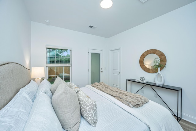 bedroom featuring wood finished floors, visible vents, and baseboards