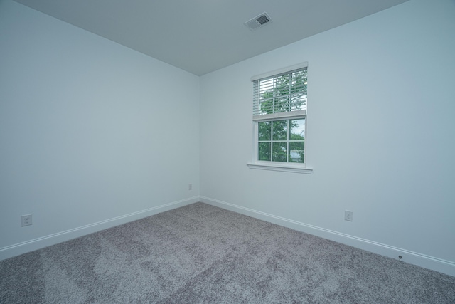 carpeted spare room with visible vents and baseboards