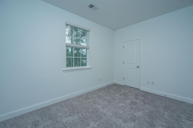 carpeted spare room with visible vents and baseboards