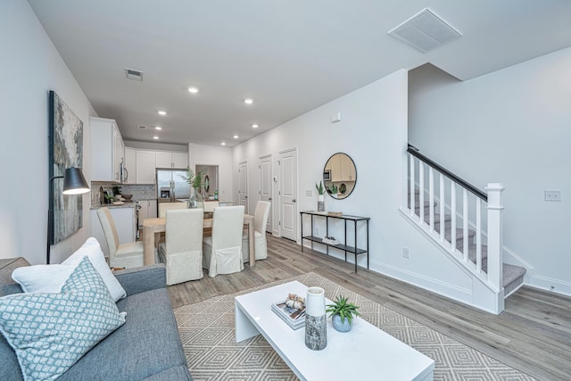 living room featuring light wood-style floors, stairs, visible vents, and recessed lighting