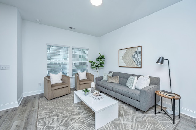 living area with light wood-style floors, visible vents, and baseboards