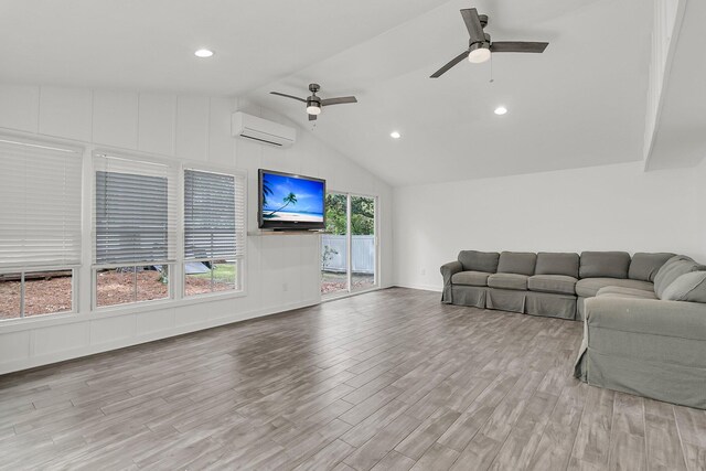 living area with a wall mounted air conditioner, ceiling fan, wood finished floors, and vaulted ceiling