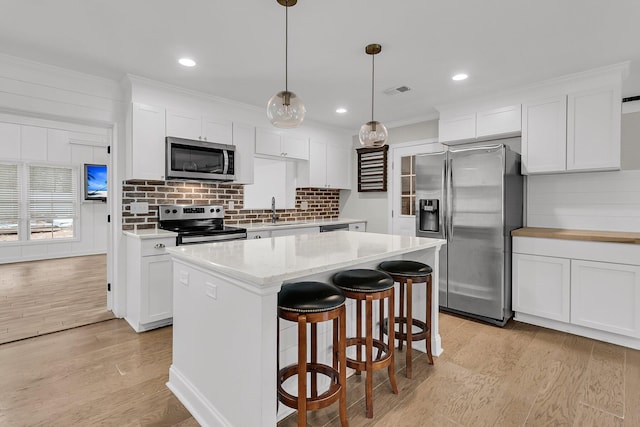 kitchen with white cabinetry, appliances with stainless steel finishes, a sink, and light wood-style floors