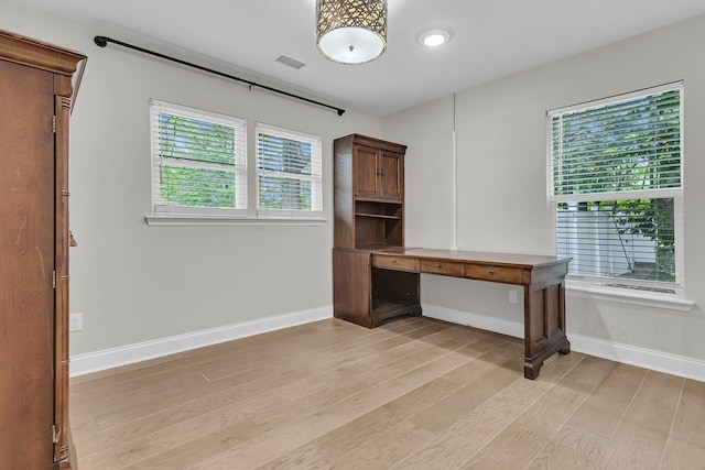 unfurnished office featuring light wood-style floors, baseboards, and visible vents
