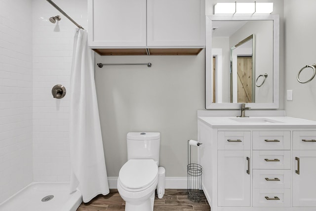 full bathroom with vanity, wood finished floors, toilet, baseboards, and a shower stall