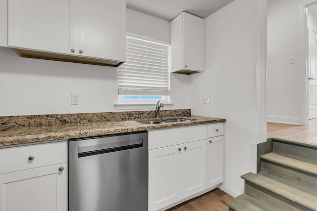 kitchen featuring stainless steel dishwasher, baseboards, a sink, and light wood-style floors