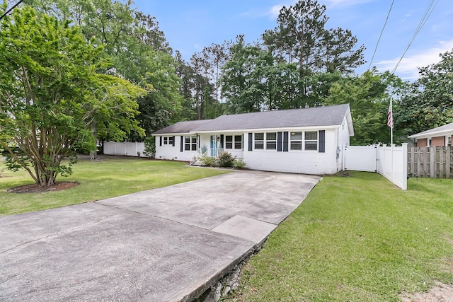 ranch-style house featuring fence, a front lawn, brick siding, a gate, and driveway
