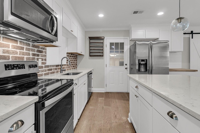 kitchen with visible vents, crown molding, a sink, white cabinets, and stainless steel appliances