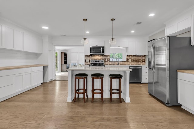 kitchen with white cabinets, stainless steel appliances, a breakfast bar, and decorative backsplash