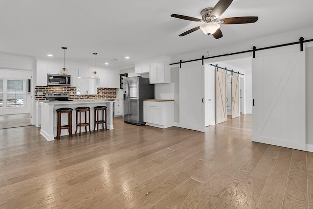 living area featuring light wood-type flooring, a barn door, ceiling fan, and recessed lighting