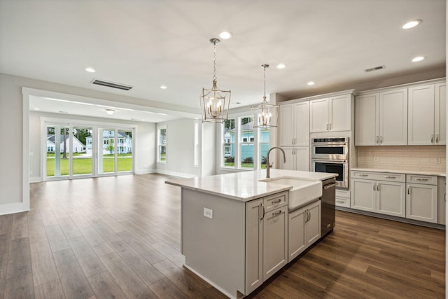 kitchen featuring visible vents, double oven, open floor plan, and a sink