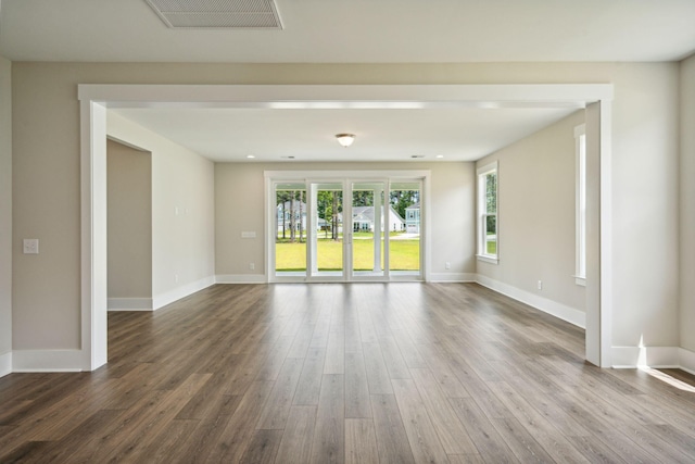 empty room featuring baseboards, visible vents, and dark wood-style flooring