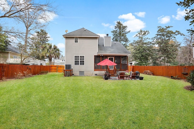 rear view of property featuring a sunroom, roof with shingles, a chimney, a yard, and a fenced backyard