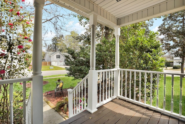 wooden terrace with a lawn and covered porch