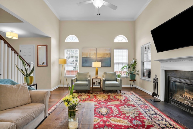 living room featuring stairway, crown molding, baseboards, and wood finished floors